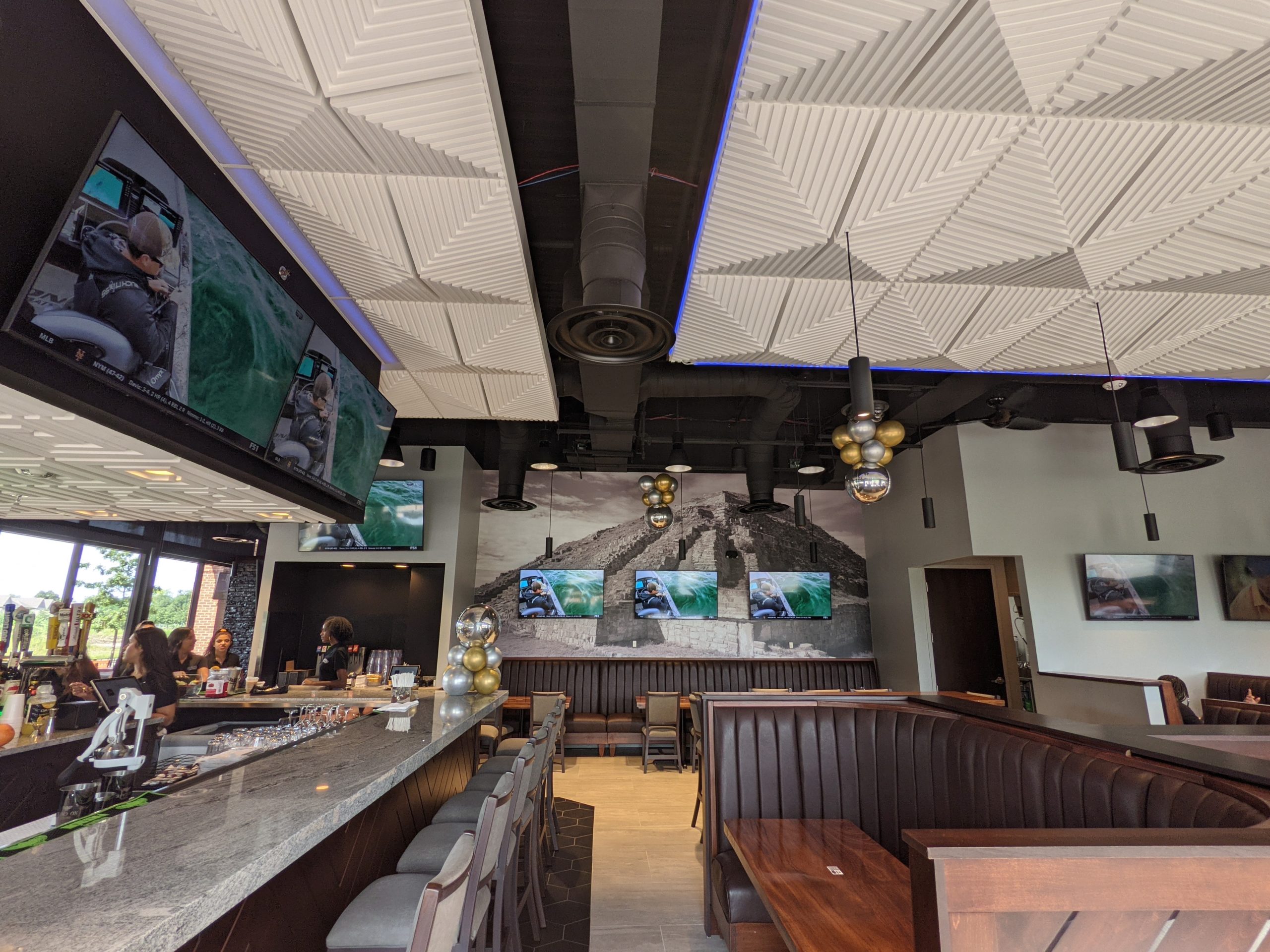 restaurant booth and bar space facing wall of tvs